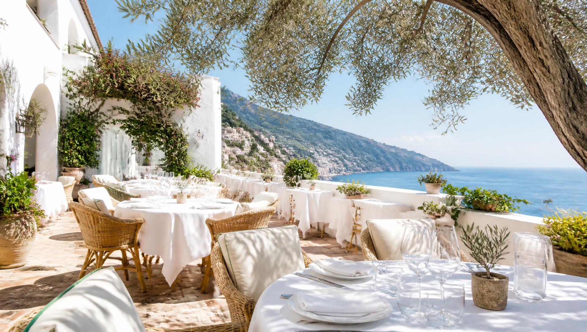 Sun-drenched Italian terrace with white linen tables under a clear blue sky at midday